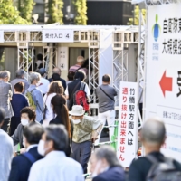 People line up to receive a COVID-19 vaccine shot at a mass inoculation center in Tokyo\'s Otemachi district on Monday. | KYODO