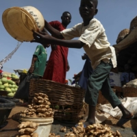 A boy pours water into a container to wash fresh ginger at a market in Kaduna, Nigeria. | REUTERS 