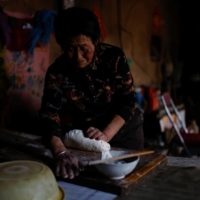 Ding Yinhua, 69, a shepherd, kneads dough for next day\'s noodles at her house in Minqin county, Wuwei.  | REUTERS 