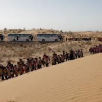 Children walk next to a sand dune on the outskirts of Wuwei during a voluntary tree-planting event organized by their school and the Wang family. | REUTERS 