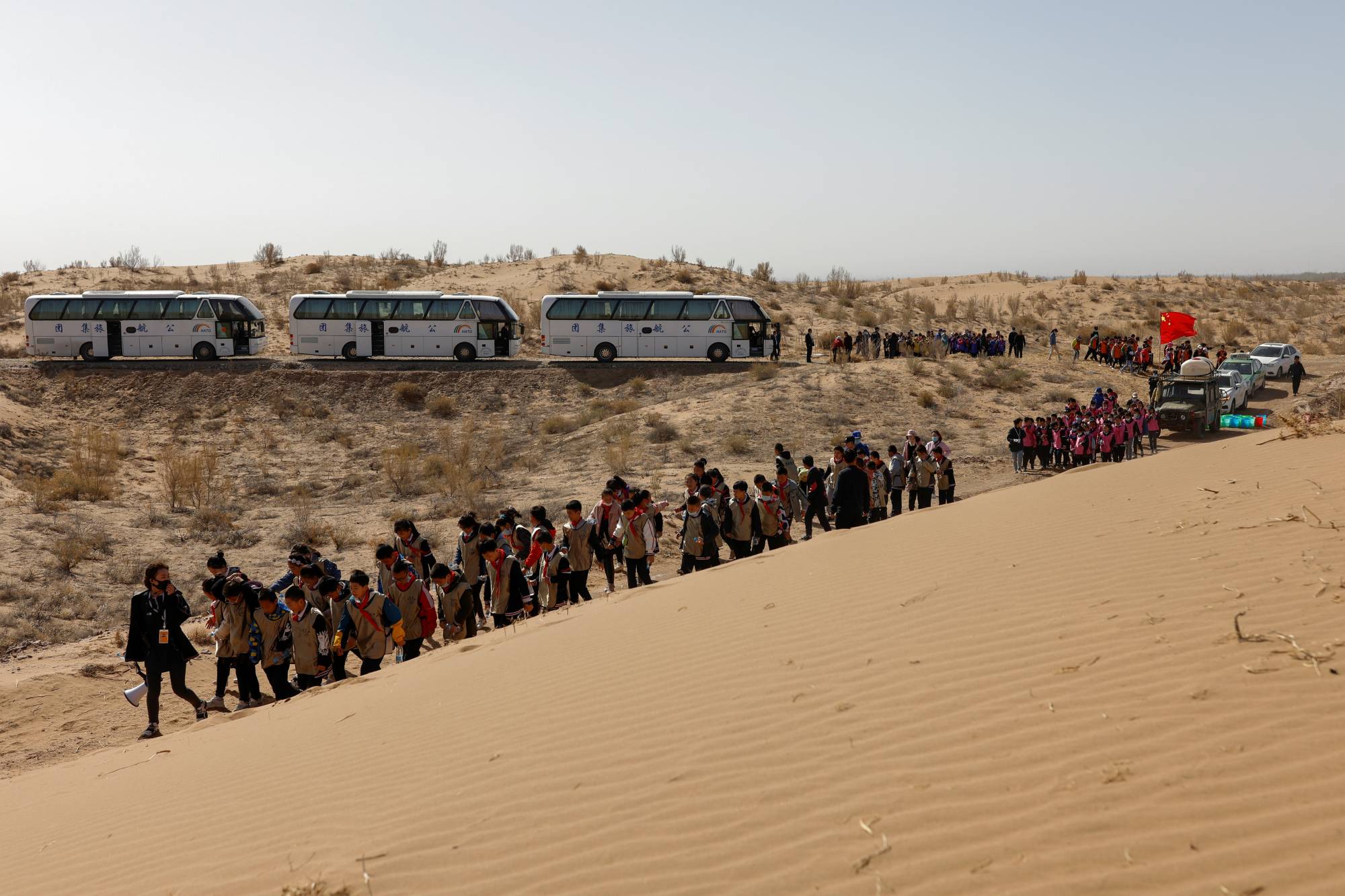 Children walk next to a sand dune on the outskirts of Wuwei during a voluntary tree-planting event organized by their school and the Wang family. | Reuters 