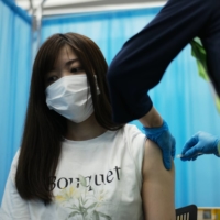 A nurse receives a vaccine dose on Sunday in Tokyo\'s Shinjuku Ward.  | RYUSEI TAKAHASHI
