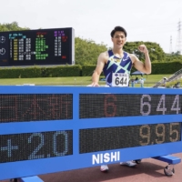 Yamagata poses with a display showing his new national-record 100 time of 9.95 seconds on Sunday at Yamata Sports Park. | KYODO