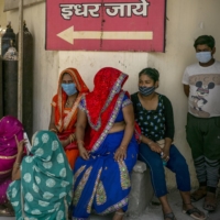 People gather next to oxygen cylinders at the Sarojini Naidu Medical College and Hospital in Agra, in Uttar Pradesh, India, on Sunday. | BLOOMBERG