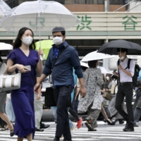 People walk in the rain in Tokyo on Monday as the rainy season started in the Kanto region. | KYODO