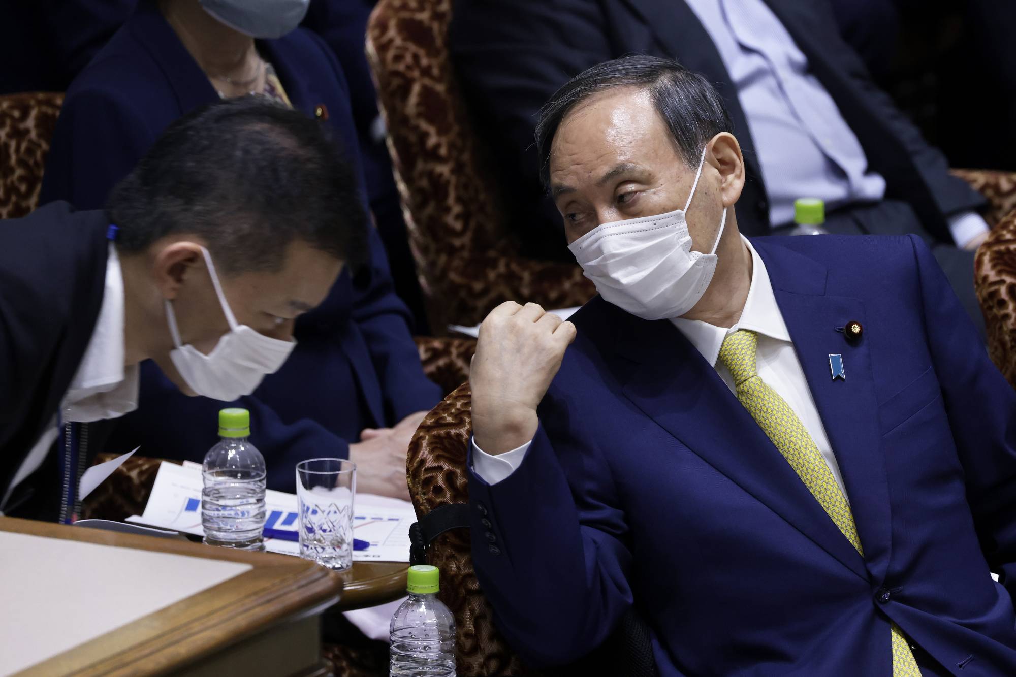 Prime Minister Yoshihide Suga confers with a staff member in the Diet's Upper House in Tokyo on June 7. | BLOOMBERG