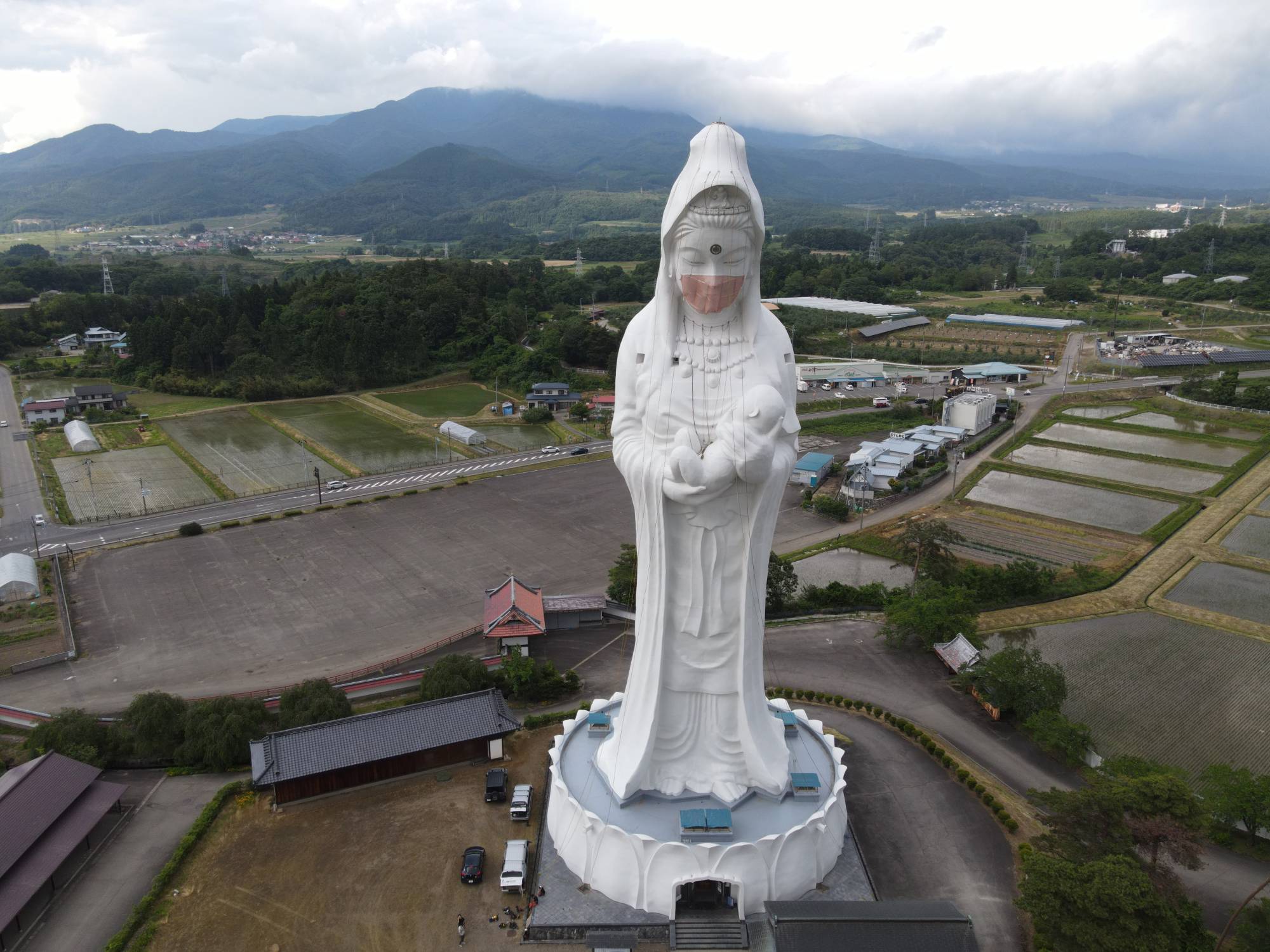 A drone picture shows a mask placed on a giant statue of Buddhist goddess Kannon at Houkokuji Aizu Betsuin temple in Aizuwakamatsu, Fukushima Prefecture, on Tuesday. | OISO ALL SUPPORT / via REUTERS