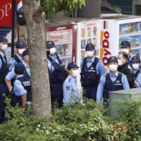 Police officers gather outside a building in which a female worker at an internet cafe is being held hostage by a male customer, on Friday in Saitama. | KYODO