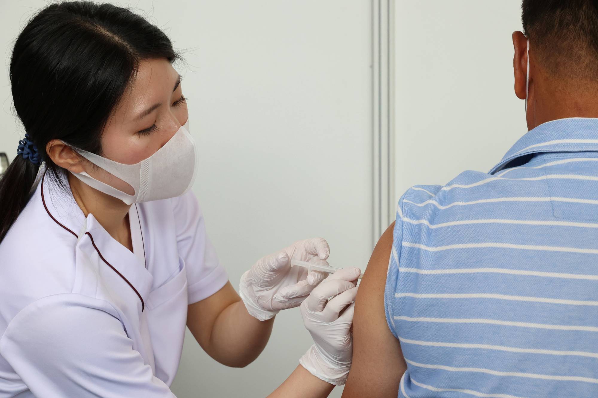 A man gets an injection of a COVID-19 vaccine at the Tokyo Metropolitan Government office in the capital Friday. | Pool / via REUTERS