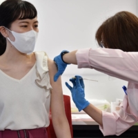 A cabin crew member of Japan Airlines receives the Moderna COVID-19 vaccine on the first day of the company\'s workplace vaccination campaign at Haneda Airport in Tokyo on June 14. | AFP-JIJI