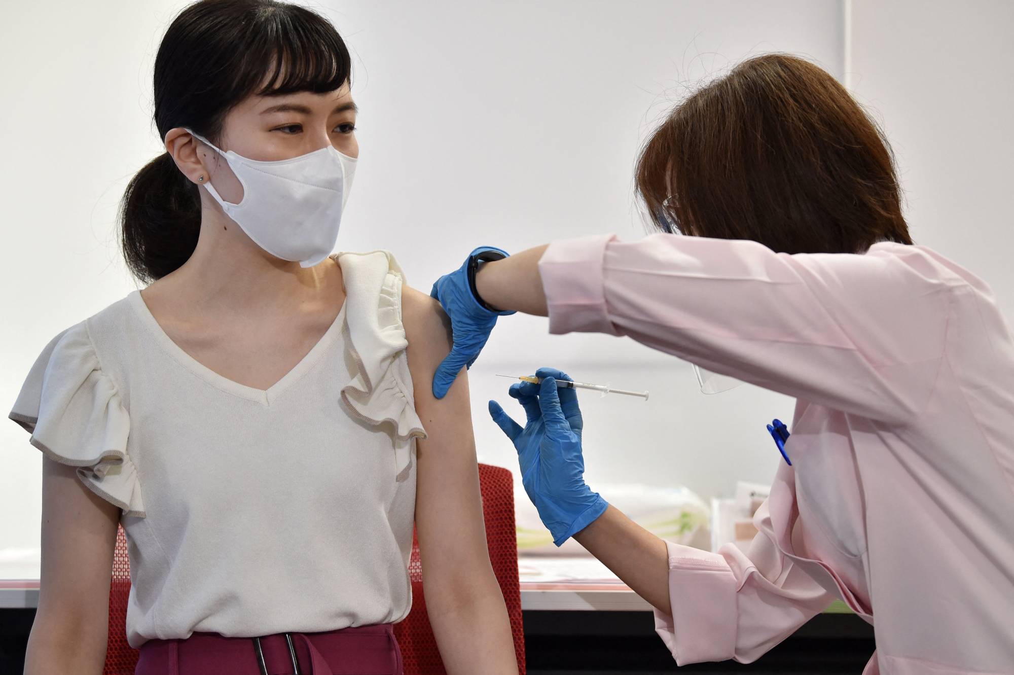 A cabin crew member of Japan Airlines receives the Moderna COVID-19 vaccine on the first day of the company's workplace vaccination campaign at Haneda Airport in Tokyo on June 14. | AFP-JIJI