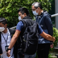 Cheung Kim Hung (right), CEO and executive director of Next Digital limited, is escorted by police from the offices of the Apple Daily newspaper to a vehicle in Hong Kong on Thursday, after police arrested the chief editor and four executives of the pro-democracy newspaper. | AFP-JIJI