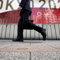 A businessman walks past an advertisement for Tokyo 2020 Olympic and Paralympic Games in the capital on Friday. | REUTERS