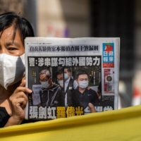 A supporter holds a copy of the Apple Daily newspaper ahead of a court appearance by Next Digital CEO Cheung Kim-hung and Apple Daily Editor-in-Chief Ryan Law in Hong Kong on Saturday.  | Bloomberg