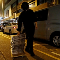 A supporter of the Apple Daily newspaper wheels a stack of the paper\'s Friday edition. | REUTERS 