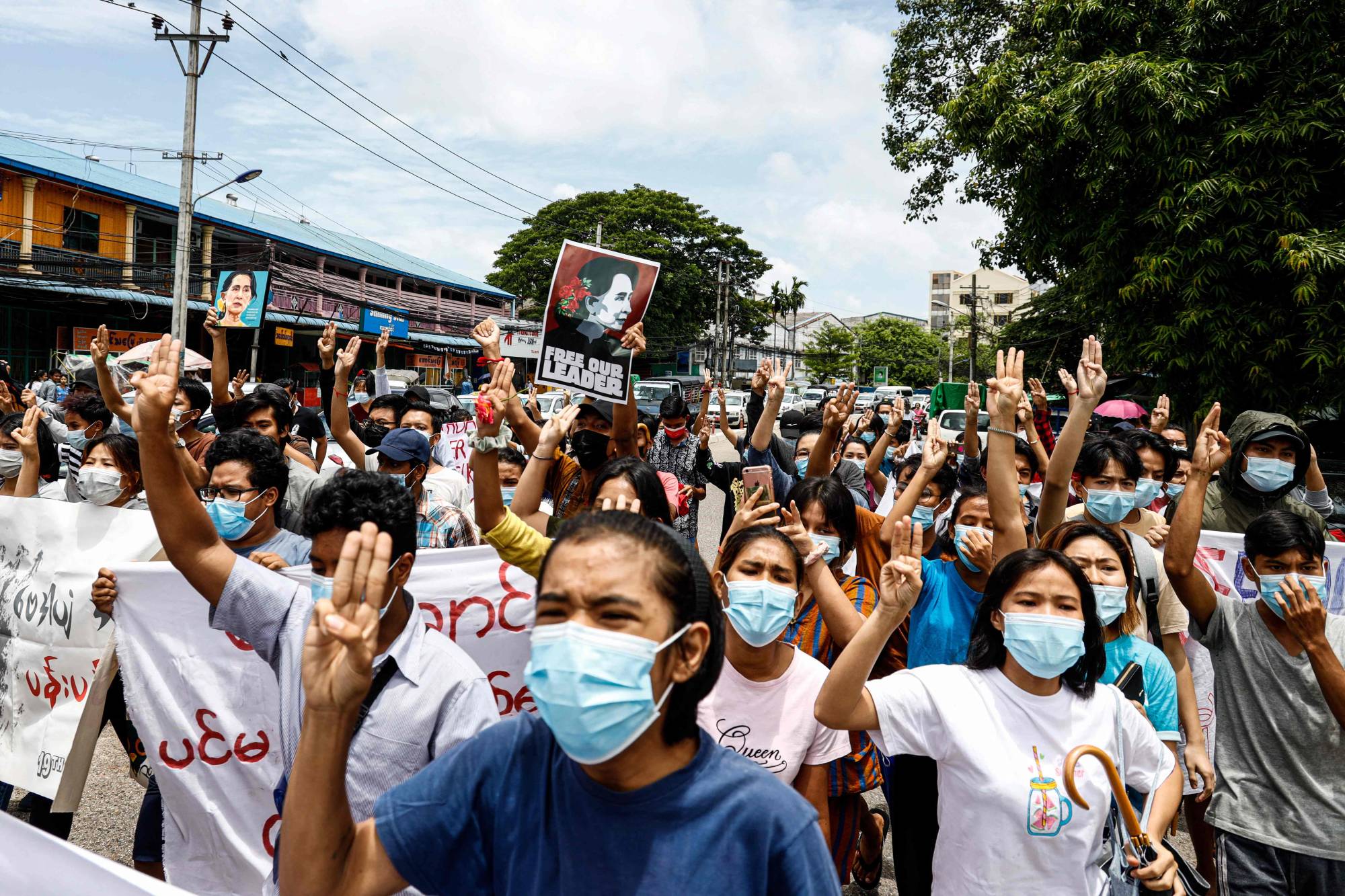 Protesters give the three-finger salute and hold posters of Myanmar's detained civilian leader, Aung San Suu Kyi, to mark her birthday as they take part in a demonstration against the military coup in Yangon on Saturday. | AFP-JIJI