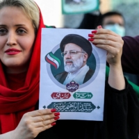 A woman holds a picture of Iran\'s newly elected president, Ebrahim Raisi, as supporters celebrate his victory in Imam Hussein square in Tehran on Saturday.  | AFP-JIJI