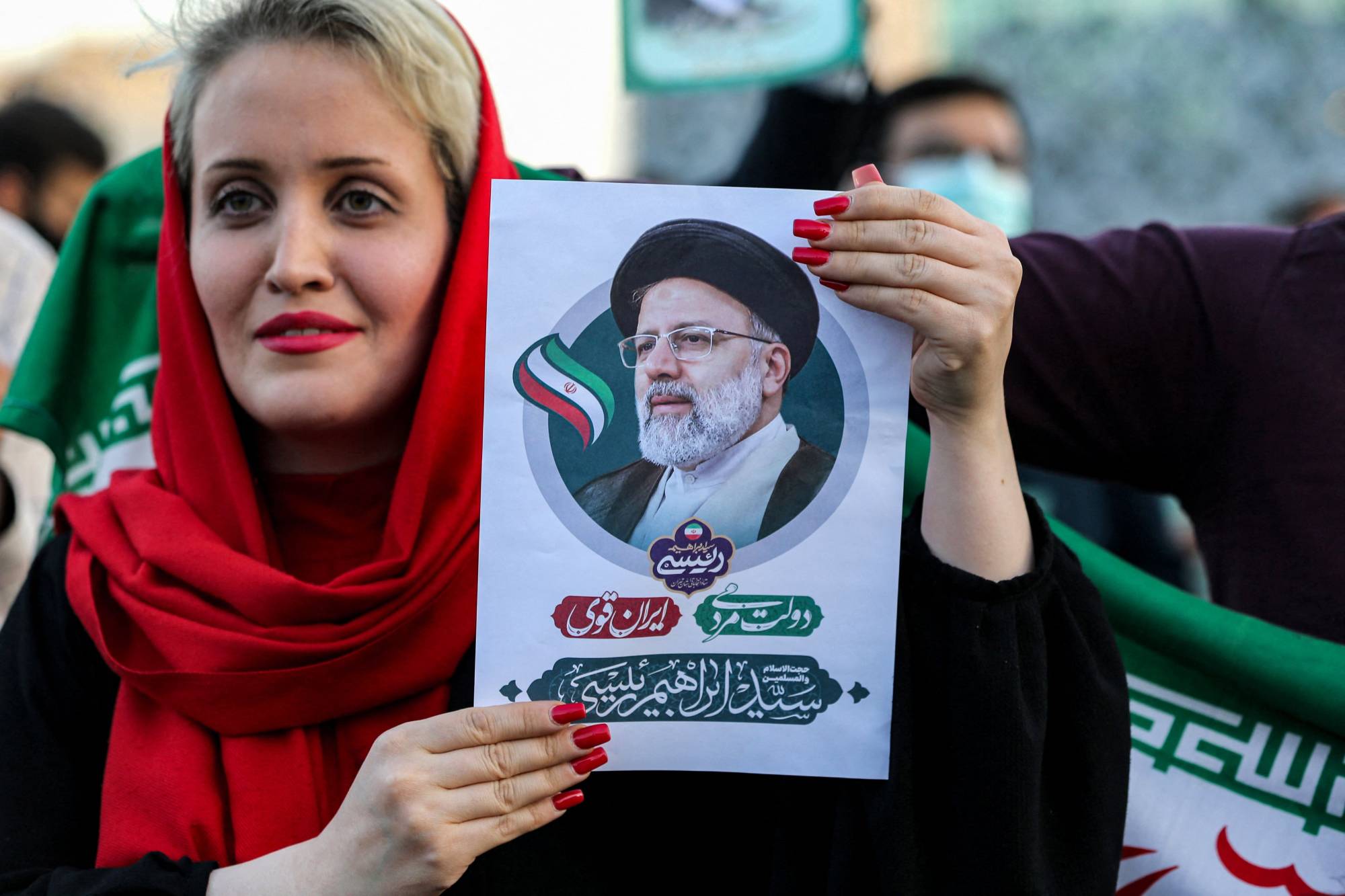 A woman holds a picture of Iran's newly elected president, Ebrahim Raisi, as supporters celebrate his victory in Imam Hussein square in Tehran on Saturday.  | AFP-JIJI
