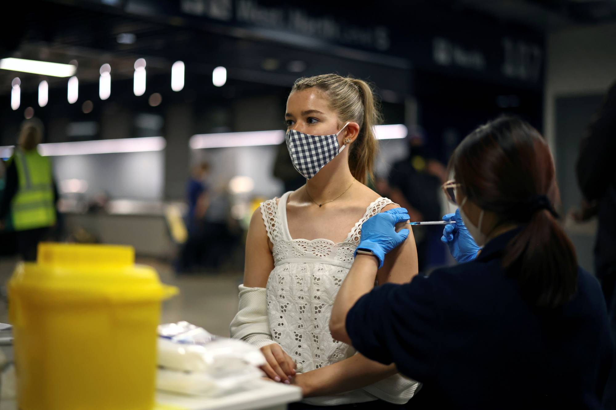A person receives a dose of the Pfizer-BioNTech COVID-19 vaccine at a mass vaccination center in London on Sunday.  | REUTERS 