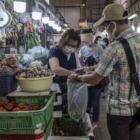 A Book Punch employee buys vegetables at a wet market in Hong Kong on June 7. Fresh greens are among the unusual rewards that the shop offers to customers. | LAM YIK FEI / THE NEW YORK TIMES