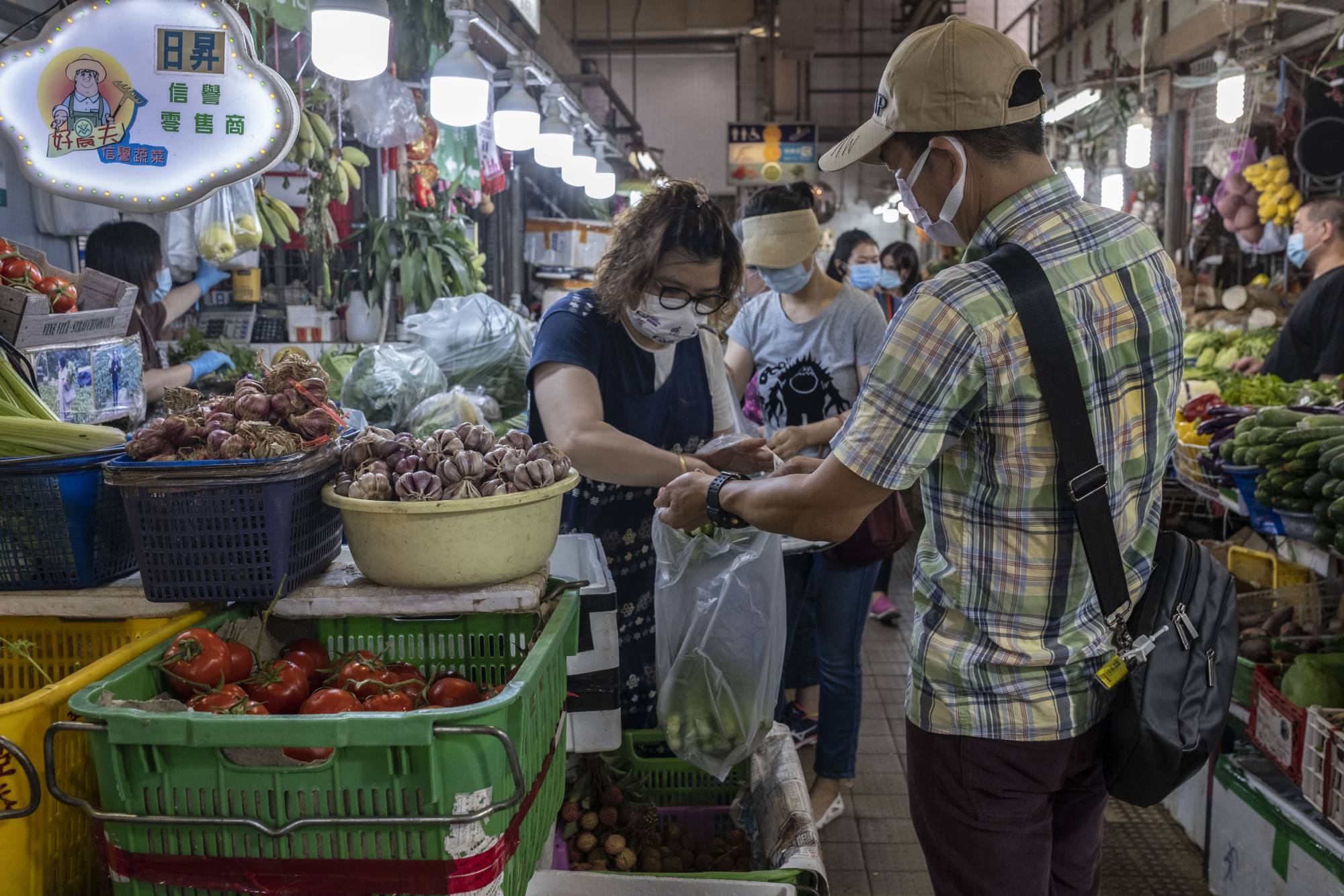 A Book Punch employee buys vegetables at a wet market in Hong Kong on June 7. Fresh greens are among the unusual rewards that the shop offers to customers. | Lam Yik Fei / The New York Times