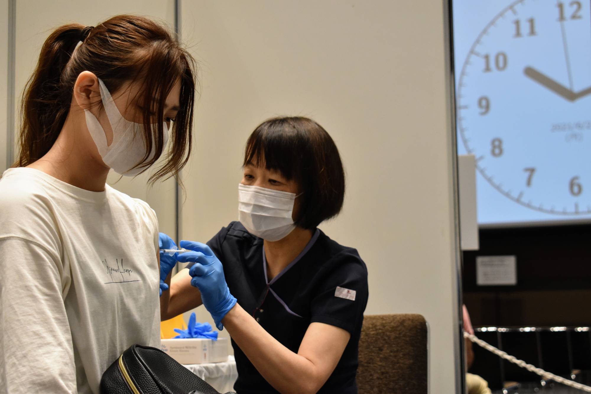 A woman receives a Moderna Inc. shot at Toranomon Hills in Tokyo, a skyscraper operated by Mori Building Co., as the property management firm moves ahead with the inoculation of its employees. | TOMOHIRO OSAKI