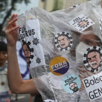 A demonstrator takes part in a protest against Brazilian President Jair Bolsonaro\'s handling of the COVID-19 pandemic, in Rio de Janeiro on Saturday. Brazil is also facing an election battle next year, with a resurgent left looking to unseat right-wing Bolsonaro. | AFP-JIJI