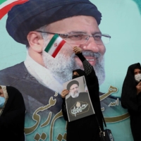 A supporter of Ebrahim Raisi displays his portrait during a celebratory rally for his presidential election victory in Tehran on Saturday.  | WEST ASIA NEWS AGENCY / VIA REUTERS 