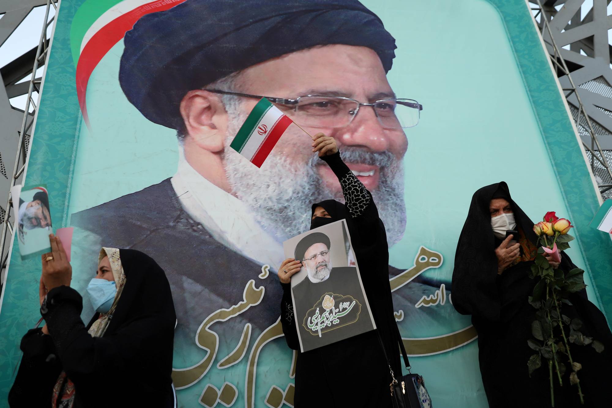 A supporter of Ebrahim Raisi displays his portrait during a celebratory rally for his presidential election victory in Tehran on Saturday.  | WEST ASIA NEWS AGENCY / VIA REUTERS 