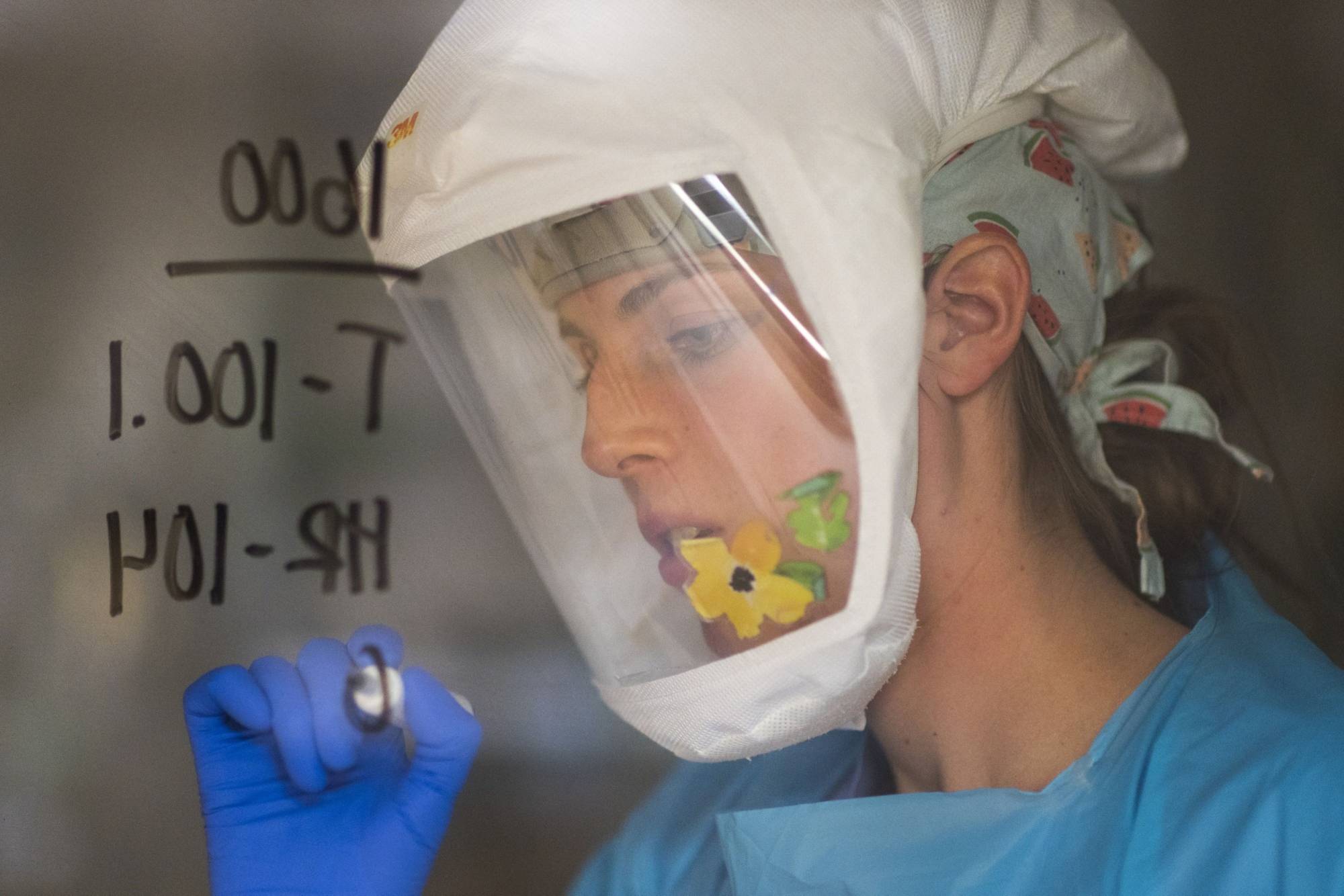 A nurse writes information on the window of a patient's room at a hospital in Salinas, California, in January. | BLOOMBERG 