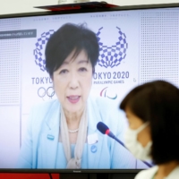 Tokyo Gov. Yuriko Koike (on screen) and Tamayo Marukawa, minister for the Tokyo Olympic and Paralympic Games, speak during a five-party meeting at Harumi Island Triton Square Tower Y in the capital on Monday. | POOL / VIA REUTERS