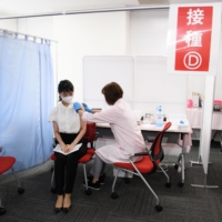 A Japan Airlines Co. employee receives a dose of the Moderna Inc. COVID-19 vaccine at a vaccination site set up at Haneda Airport in Tokyo on June 14. | BLOOMBERG