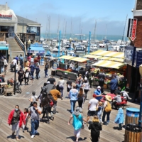People walk along Pier 39 in downtown San Francisco on June 15. San Francisco welcomes over 15 million visitors each year to the city’s waterfront.  | JIM WILSON / THE NEW YORK TIMES