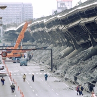 A giant crane pulls crushed cars out of debris in Kobe in January 1995.  | REUTERS