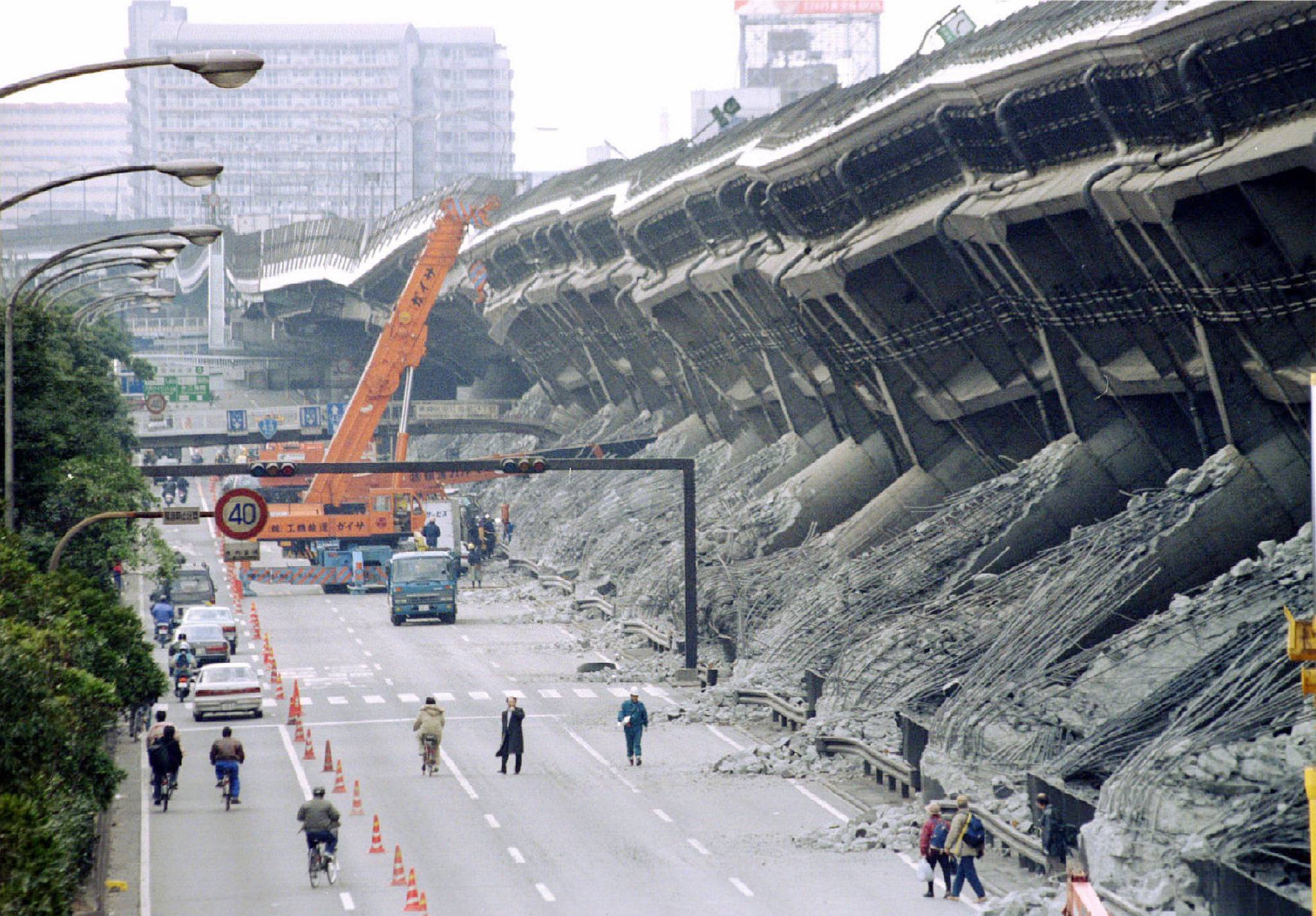 A giant crane pulls crushed cars out of debris in Kobe in January 1995. | reuters