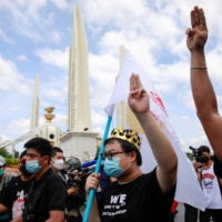 Protest leader Parit \"Penguin\" Chiwarak (center) shows a three-finger salute during a demonstration in Bangkok on Thursday to mark the 89th anniversary of the abolition of absolute monarchy.   | REUTERS 