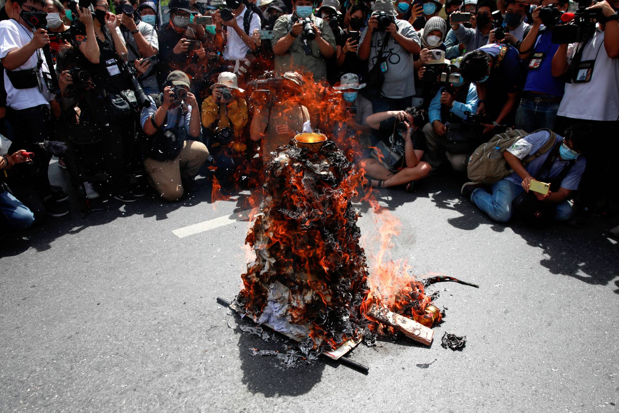 Members of the media take photos of a model of Democracy Monument set on fire by protesters in Bangkok on Thursday.  | Reuters 