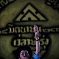 A pro-democracy activist stands in front of a large replica of the 1932 Siamese Revolution plaque in Bangkok on Thursday as they gather to commemorate the anniversary of the end of absolute monarchy.  | AFP-JIJI