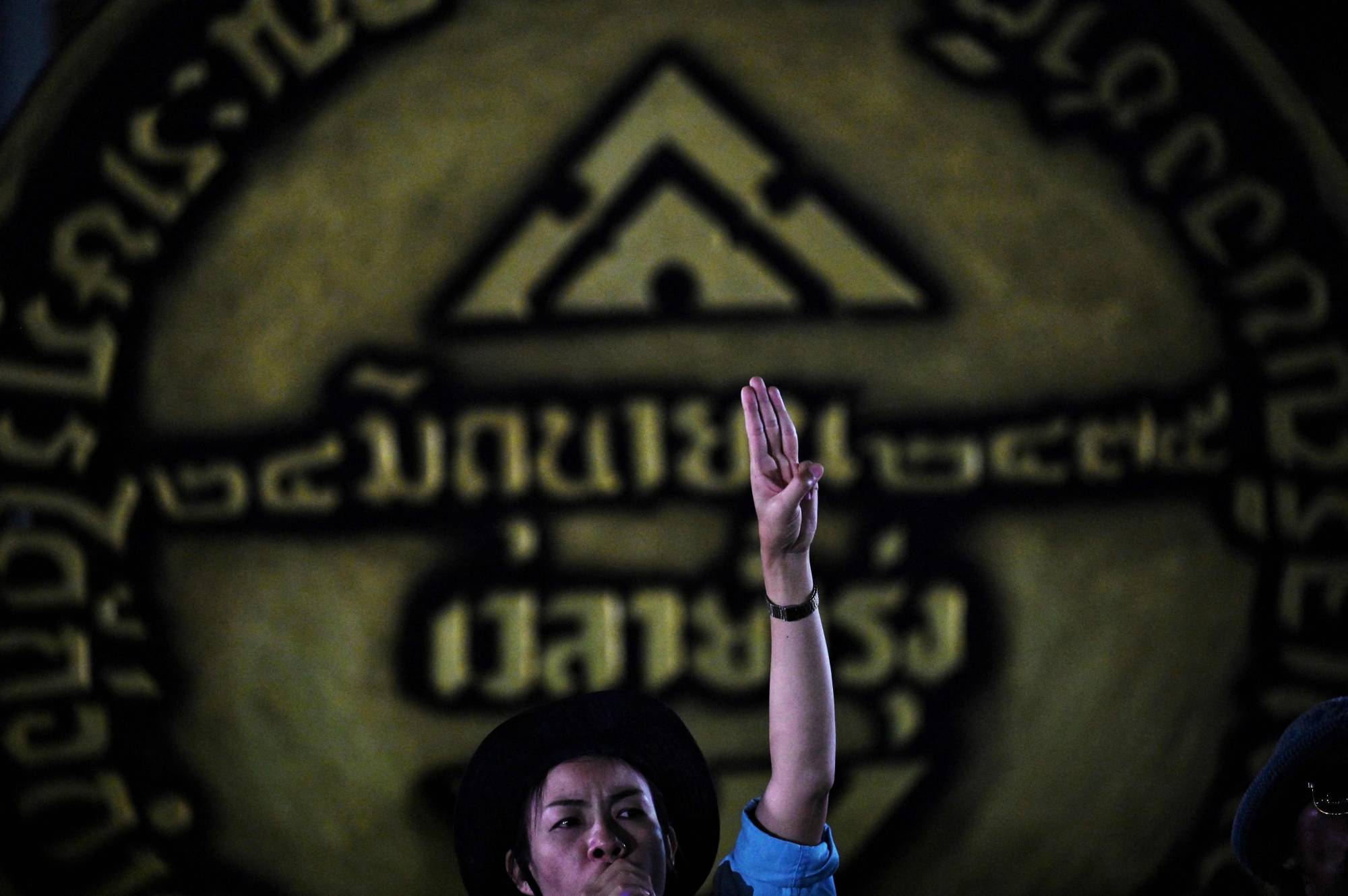 A pro-democracy activist stands in front of a large replica of the 1932 Siamese Revolution plaque in Bangkok on Thursday as they gather to commemorate the anniversary of the end of absolute monarchy.  | AFP-Jiji
