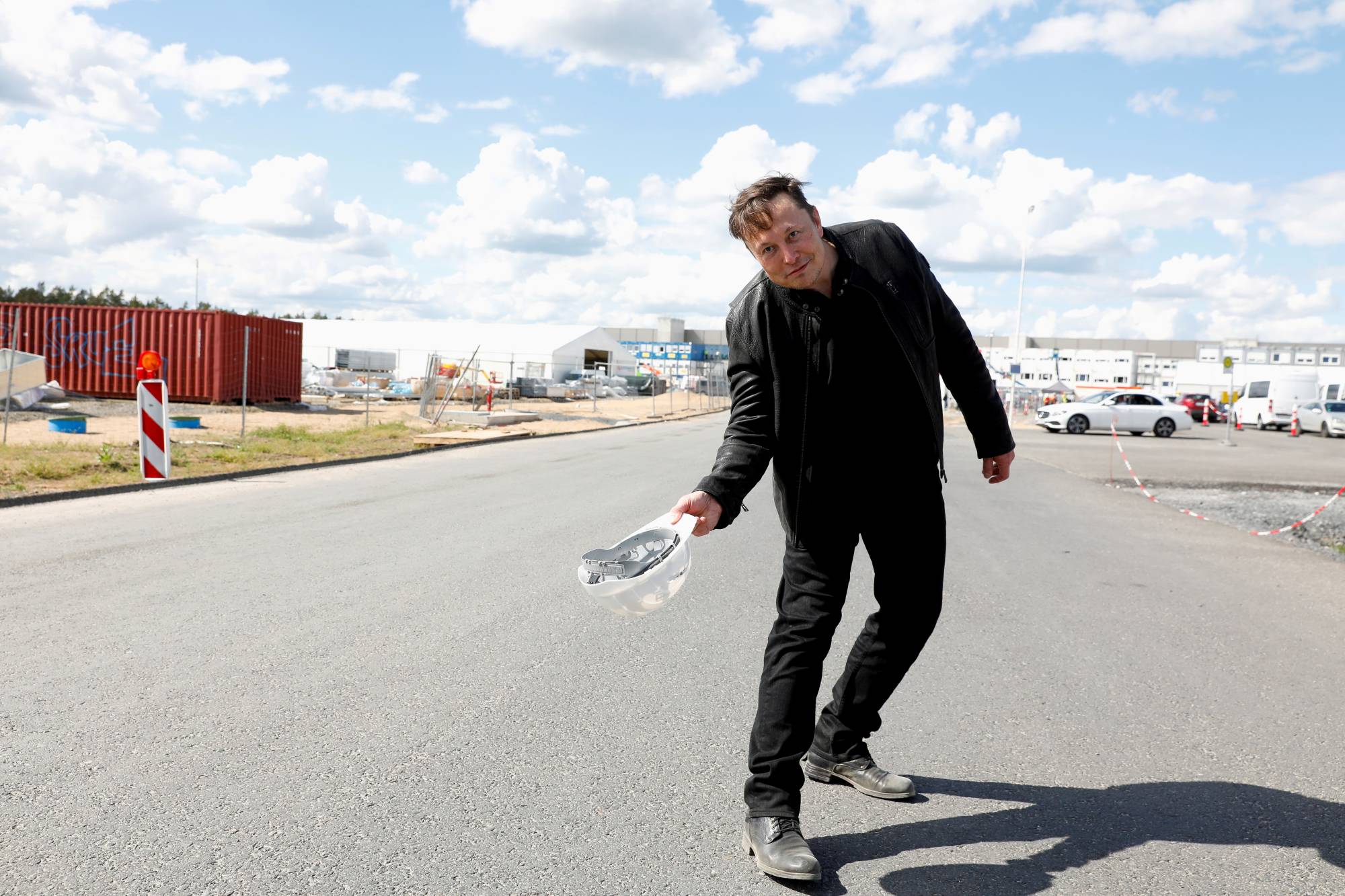 Tesla CEO Elon Musk holds a helmet as he visits the construction site of Tesla's gigafactory in Gruenheide, near Berlin, in May. | Reuters 