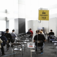 People wait to be inoculated at a vaccination site in Tokyo on Friday.  | BLOOMBERG