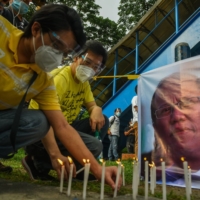 Supporters of the late President Benigno Aquino light candles during a prayer vigil outside a university where his remains lay on Friday.  | AFP-JIJI