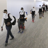 Members of the Ugandan Olympic team arrive at Narita Airport in Chiba Prefecture on June 19. Athletes and other delegation members for the Tokyo Olympics and Paralympics should be immediately isolated if they arrive in Japan with a person infected with the novel coronavirus, the organizing committee\'s senior officer said Sunday. | KYODO