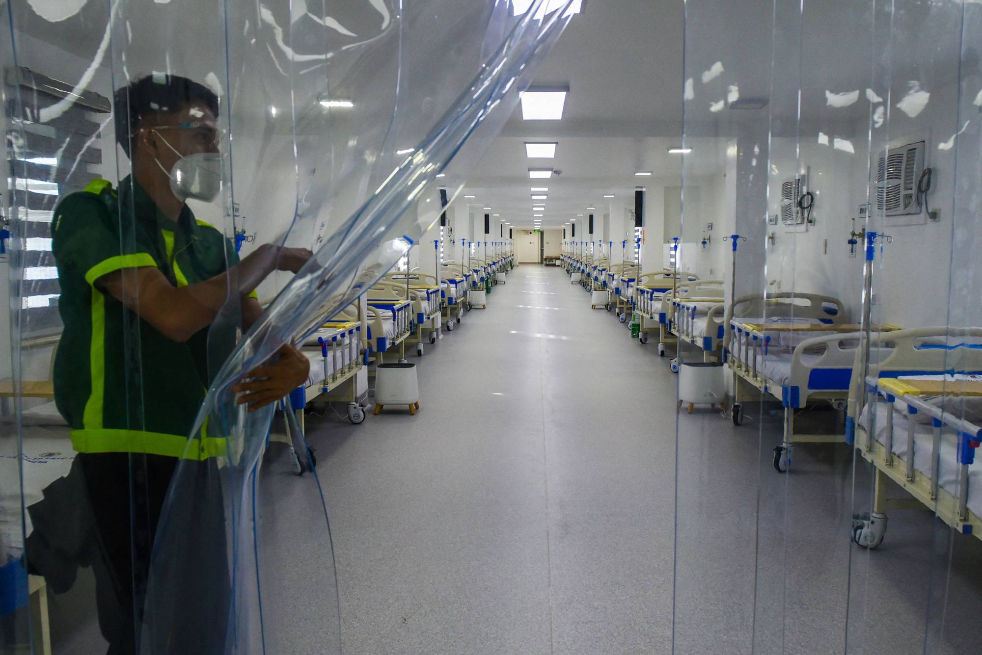 A worker holds a plastic divider inside a field hospital for Covid-19 patients at a park in Manila on June 24. | AFP-JIJI