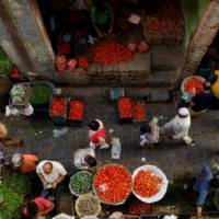 People shop at a crowded wholesale vegetable market after authorities eased coronavirus restrictions in Delhi on June 23.  | REUTERS