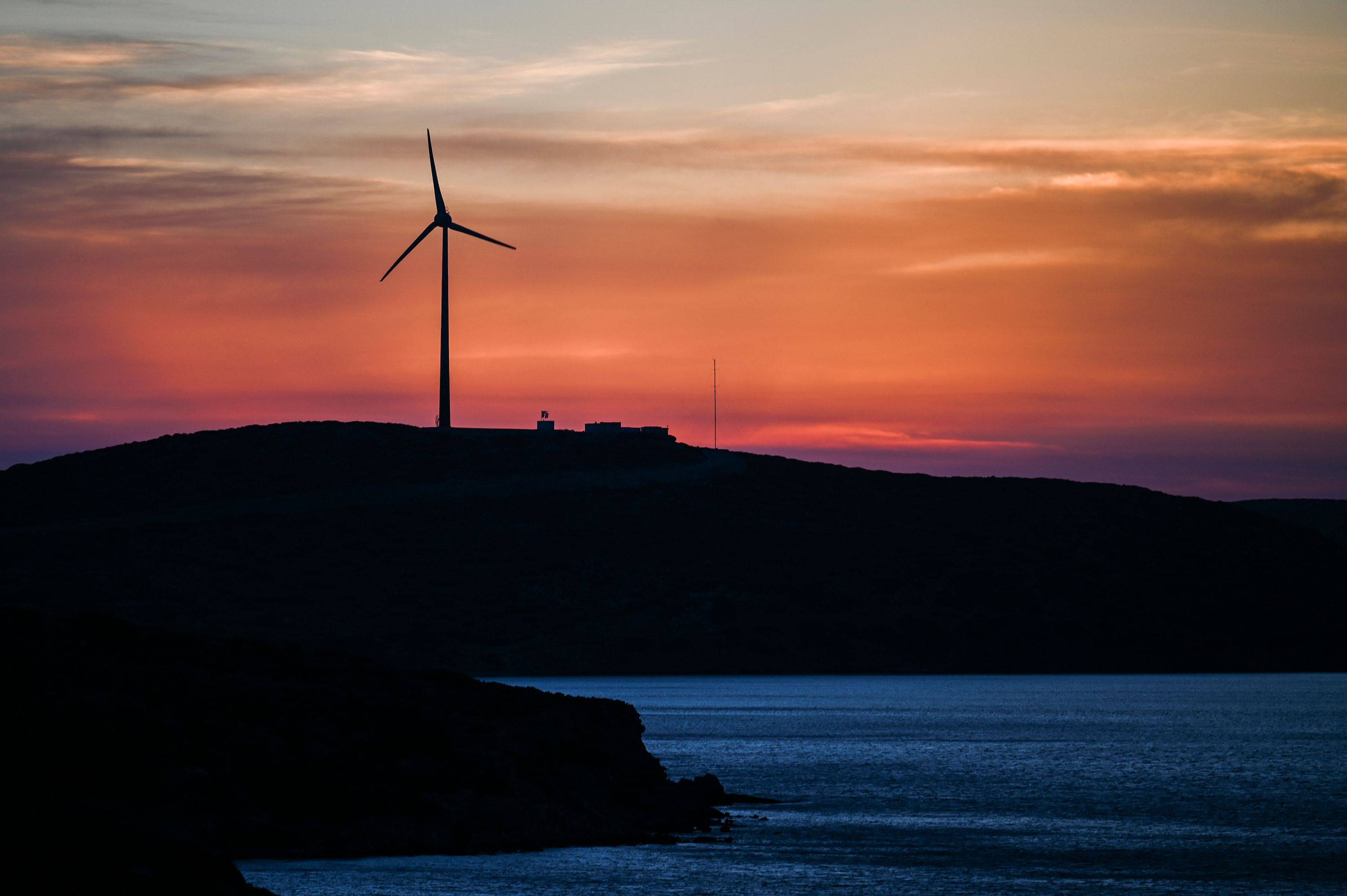 A wind turbine in Tilos island in Greece in June. Under Japan's draft basic energy policy for fiscal 2030, renewable energy will account for 36% to 38% of total power production, up from 22% to 24% in the previous plan. | AFP-JIJI