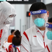 Chinese Basketball Association President Yao Ming (center) stands with staffers during the quarantine process after arriving at Narita Airport in Chiba Prefecture on July 19 ahead of the Tokyo Games. | REUTERS