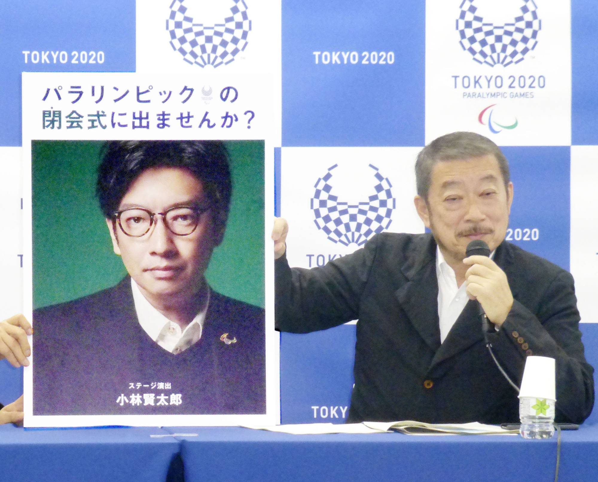 Kentaro Kobayashi (pictured on a poster) is introduced as the opening ceremony director for the Olympics and Paralympics during a news conference in December 2019. | KYODO