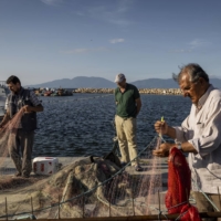Fishing workers repairing their nets at the harbor in Misakca, Turkey, on the Sea of Marmara. | IVOR PRICKETT / THE NEW YORK TIMES