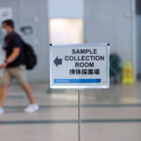 A sign indicates the location PCR sample collection room at the main press center ahead of the Tokyo 2020 Olympic Games. | REUTERS
